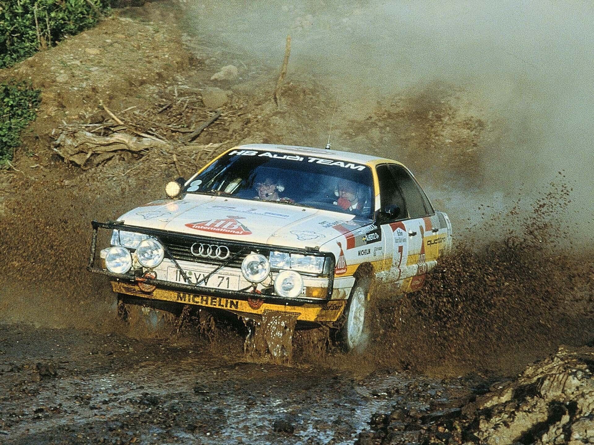 A picture showing an Audi 200 quattro rally car driving through water splash in Africa in 1987.